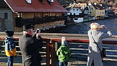 Rozvodněnou Vltavu si fotí turisté.