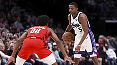 De�Aaron Fox (vpravo) ze Sacramento Kings úto�í v zápase s Portland Trail...