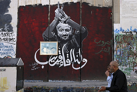 Mui procházejí kolem portrétu Palestince Marvána Barghútího v Betlém na...