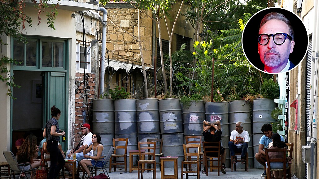 Lidé sedí p�ed kavárnou p�ed zablokovanou silnicí s barely a pytli s pískem u...