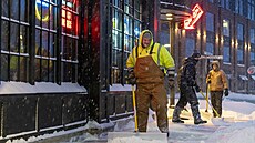 Dlníci odklízejí sníh z chodník v Ankeny ve stát Iowa. (12. ledna 2024)