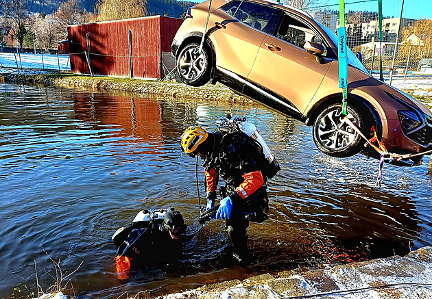 Řidička na parkovišti prorazila plot a sjela do nádrže, auto vytahovali jeřábem