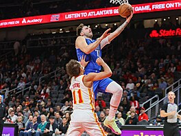 Luka Don�i� nají�dí na ko�, brání ho Trae Young.