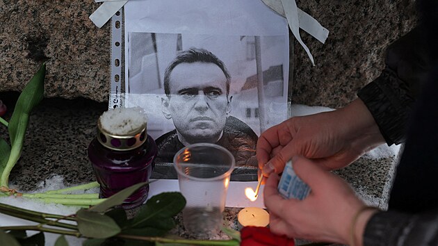 ena zapaluje svku u portrtu ruskho opozinho vdce Alexeje Navalnho u pamtnku obtem politickch repres v Petrohrad. (16. nora 2024)