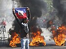 Demonstrant drí haitskou vlajku bhem protest poadujících odstoupení...