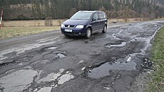 Takto rozbitá je po letoní zim silnice z Holovic na Karlovice na Bruntálsku.