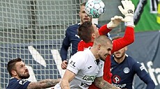 Karvinský obránce Douglas Bergqvist naskakuje do souboje s branká�em Slovácka...