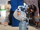Palestinská dívka si pelévá svj díl pitné vody, který dostala ve mst Rafáh...