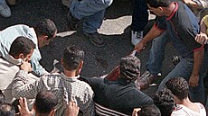 Palestinec tahá za zakrvácené triko izraelského vojáka leícího na zemi ve...