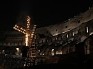 Dlník zapaluje svíky na kíi v Koloseu ped zaátkem pochodového prvodu...