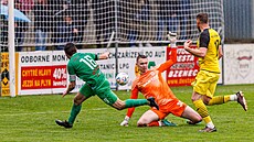 Petr Kasala z Bzence (v zeleném) dává gól do sít Strání v utkání divize E....