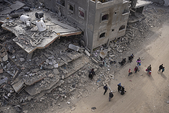 Palestinci procházejí zničenými budovami po izraelské letecké a pozemní...