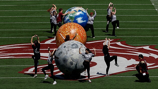 Lid tan kolem vyobrazen Zem, Slunce a Msce na stadionu Saluki Stadium ve stt Illinois ped plnm zatmnm Slunce, pi nm Msc zakryje Slunce. (8. dubna 2024)