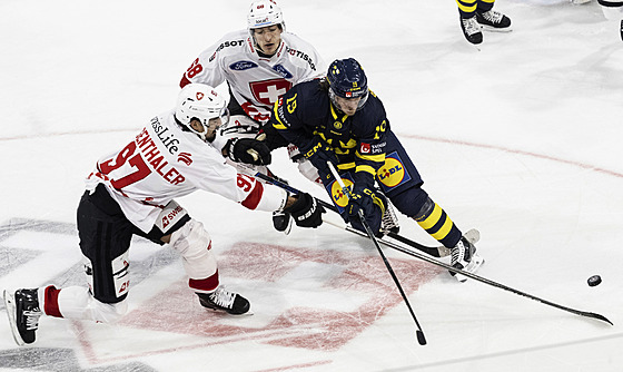 Švýcarští hokejisté  Jonas Siegenthaler (vlevo) a  Fabrice Herzog brání Švéda...