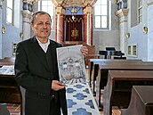 Budyský starosta Petr Kindl stojí v opravené synagoze, v ruce drí snímek z...