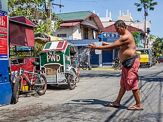 Mu polévá silnici vodou bhem horkého poasí v Manile. (28. dubna 2024)