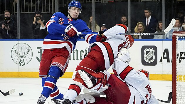 Kaapo Kakko (vlevo) z New York Rangers zamstnv Jesperiho Kotkaniemiho a branke Frederika Andersena z Caroliny.