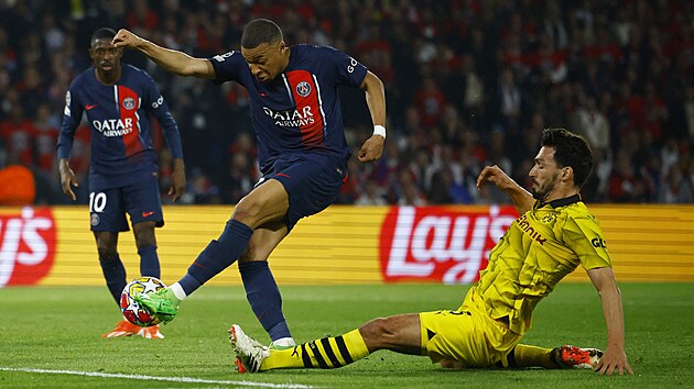 Kylian Mbappé stílí, stoper Dortmundu Mats Hummels se ho ve skluzu snaí...