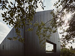 Fasádu rytmizují �ern� nat�ené lat�. Rastr je pojítkem exteriéru i interiéru,...