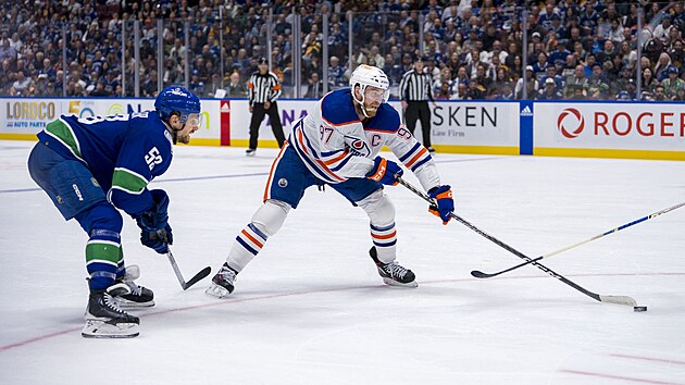 Kapitn Edmontonu Connor McDavid se natahuje po puku, ze strany ho sleduje Teddy Blueger z Vancouveru.