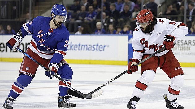 Chris Kreider (vlevo) z New York Rangers a Jalen Chatfield z Carolina Hurricanes bojuj o puk.