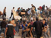 Palestinci berou krabice s humanitární pomocí z nákladních aut peváejících...