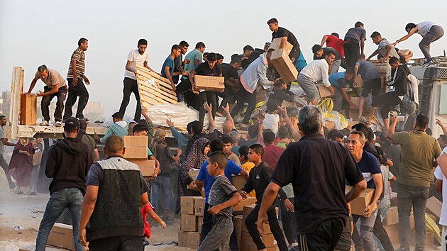 Palestinci berou krabice s humanitární pomocí z nákladních aut peváejících...