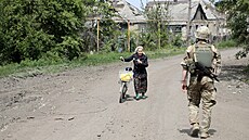 Voják prochází kolem starí eny tlaící kolo po ulici v asiv Jaru. (18....