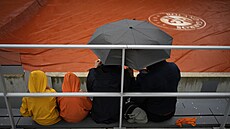 Diváci sledují kapky dopadající na zataenou plachtu kurtu na Roland Garros.