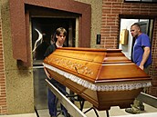 elní ást pece jihlavského krematoria, kam pracovník zasouvá rakev se zesnulým...