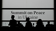 Lidé v mediálním centru před začátkem mírového summitu o Ukrajině v letovisku...