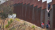 Migranti se snaí dostat pes plot steící hranici Mexika a USA. (7. ervna...