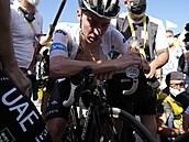 Absolutn vyerpaný slovinský cyklista Tadej Pogaar (UAE) se osvuje v cíli...