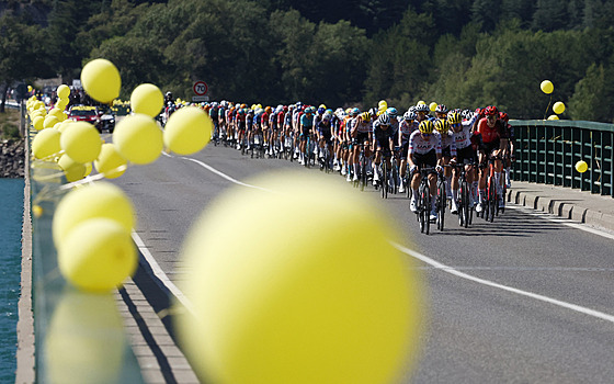 Peloton pekonává most pes Lac de Serre-Poncon v osmnácté etap Tour.