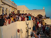 Turisté si uívají letní odpoledne na Santorini, procházejí se po bílých...