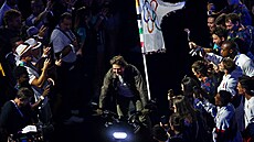 Tom Cruise odjí�dí na motorce s olympijskou vlajkou p�i slavnostním zakon�ení.