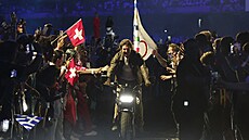 Tom Cruise odjí�dí na motorce s olympijskou vlajkou p�i slavnostním zakon�ení.