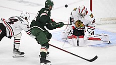 Jakub Lauko z Minnesoty v �anci p�ed branká�em  Drewem Commessem z Chicaga.