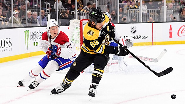 David Pastr��k z Boston Bruins sp�ch� za pukem p�ed Caidenem Guhlem z Montreal Canadiens.