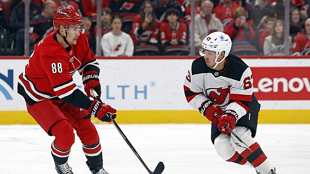 �to�n�k Caroliny Martin Ne�as (vlevo) pos�l� puk p�es obr�nce New Jersey Jespera Bratta.