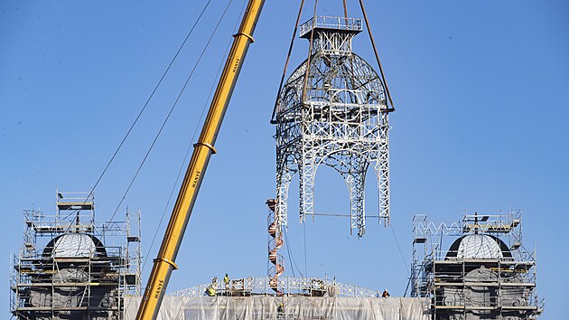 Na st�echu st�edn� ��sti Pr�myslov�ho pal�ce na V�stavi�ti v pra�sk�m Buben�i, kter� v roce 2008 vyho�ela, d�ln�ci vr�tili opravenou 26 tun t�kou konstrukci hodinov� v�e. (15. ��jna 2024)