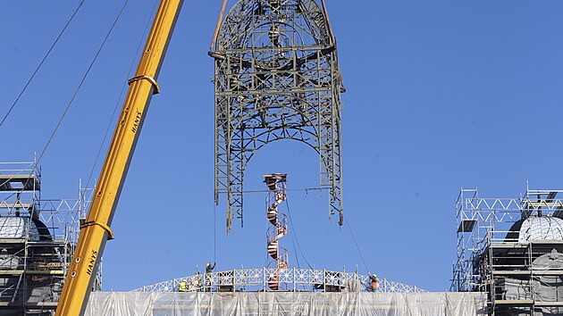 Na st�echu st�edn� ��sti Pr�myslov�ho pal�ce na V�stavi�ti v pra�sk�m Buben�i, kter� v roce 2008 vyho�ela, d�ln�ci vr�tili opravenou 26 tun t�kou konstrukci hodinov� v�e. (15. ��jna 2024)