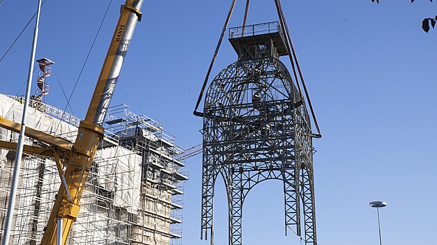 Na st�echu st�edn� ��sti Pr�myslov�ho pal�ce na V�stavi�ti v pra�sk�m Buben�i, kter� v roce 2008 vyho�ela, d�ln�ci vr�tili opravenou 26 tun t�kou konstrukci hodinov� v�e. (15. ��jna 2024)