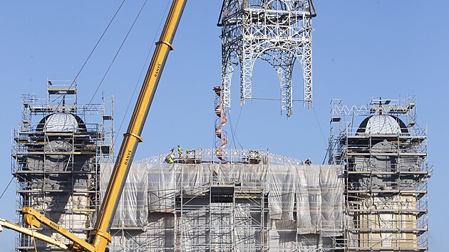 Na st�echu st�edn� ��sti Pr�myslov�ho pal�ce na V�stavi�ti v pra�sk�m Buben�i, kter� v roce 2008 vyho�ela, d�ln�ci vr�tili opravenou 26 tun t�kou konstrukci hodinov� v�e. (15. ��jna 2024)