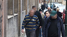 Detektivové z NCOZ odvádí jednoho ze zadr�ených  (v pruhovaném svetru) z vedení...