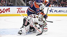 Branká� Chicaga Petr Mrázek zasahuje proti Zachu Hymanovi z Edmontonu.