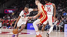 Vít Krejí z Atlanta Hawks (uprosted) brání pronikajícího Carltona Carringtona...