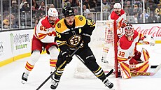 David Pastrák z Bostonu rozehrává v utkání proti Calgary. Za ním je Daniil...