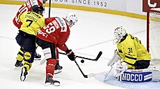 Enzo Corvi a Dario Simion z �výcarska hrnou puk p�es �védského obránce Henrika...