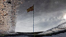 Lidé krá�ejí vedle �pan�lské vlajky s oblohou pokrytou mraky bou�e DANA. Po...